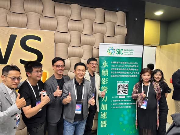 多位與會者在 SIC 永續影響力加速器的立牌旁合影